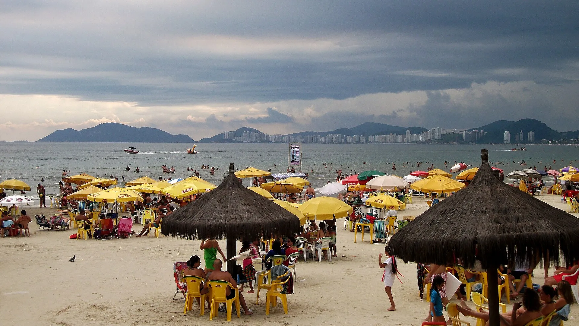 Praia da Enseada, no Guarujá, com quiosques, guarda-sóis e os morros ao fundo